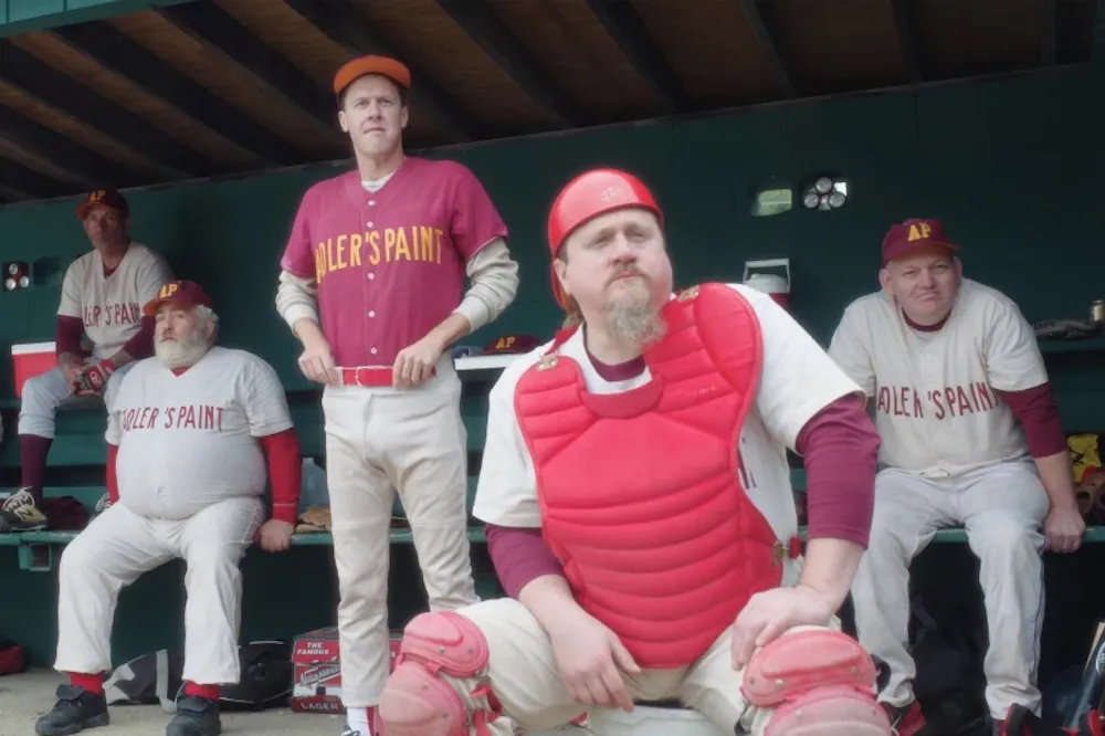 Group of baseball players look forward from dugout.