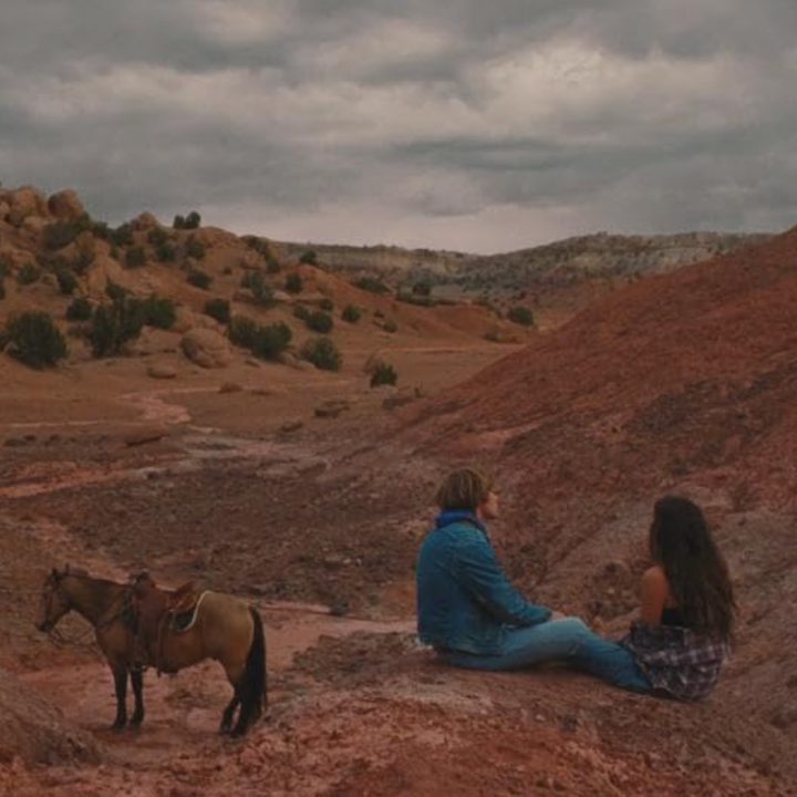 Two people and a horse in desert setting.